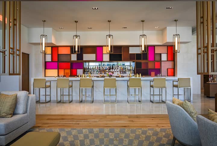 A resort bar with warm backlit shelving and ocean-view seating