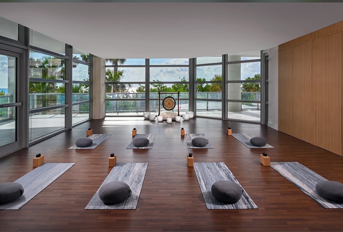 A wellness studio with yoga mats and bolsters on a wood floor