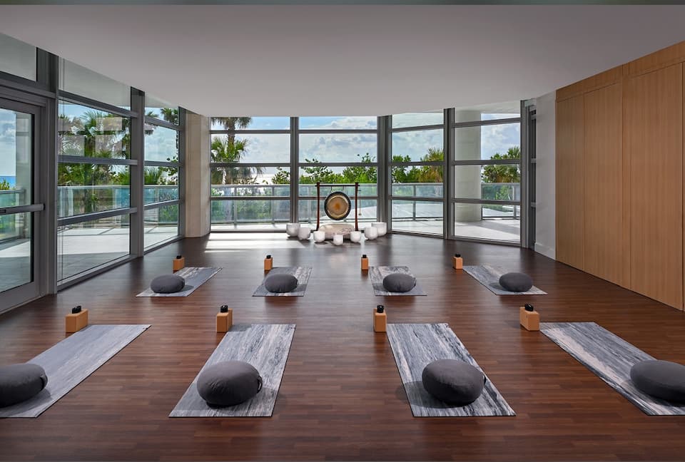 A wellness studio with yoga mats and bolsters on a wood floor