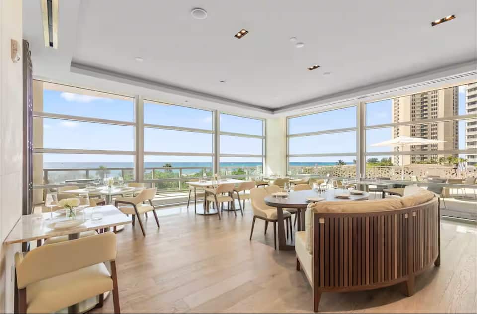 A dining lounge with tables beside floor-to-ceiling windows