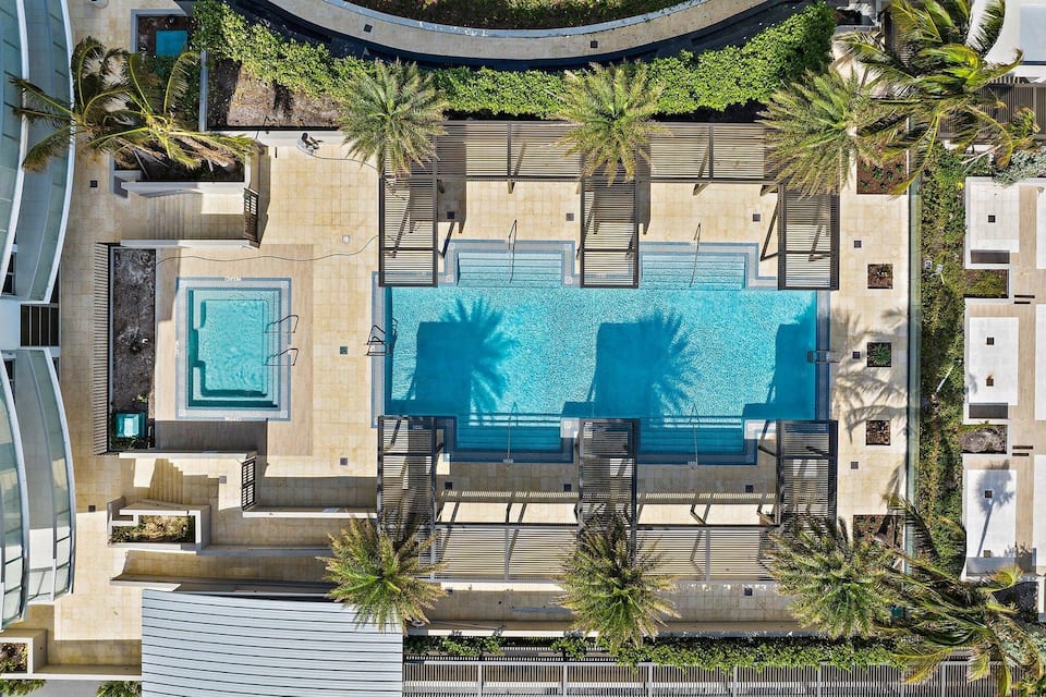 Aerial view of the resort's rooftop pools and cabanas among palms