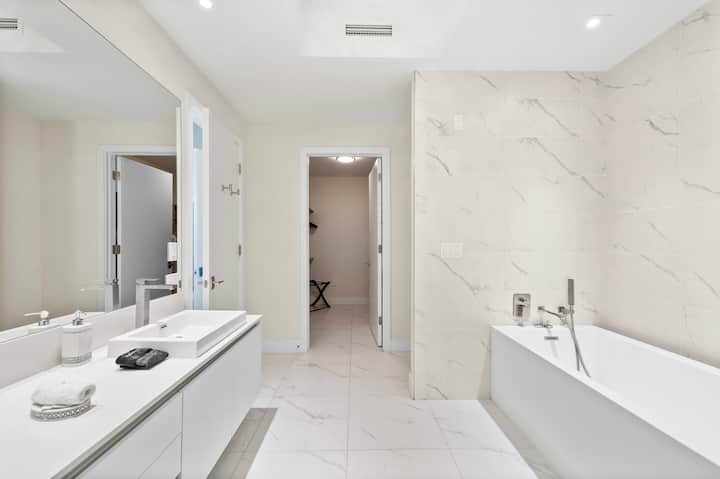 The primary bathroom with its soaking tub, twin vanities and marble walls