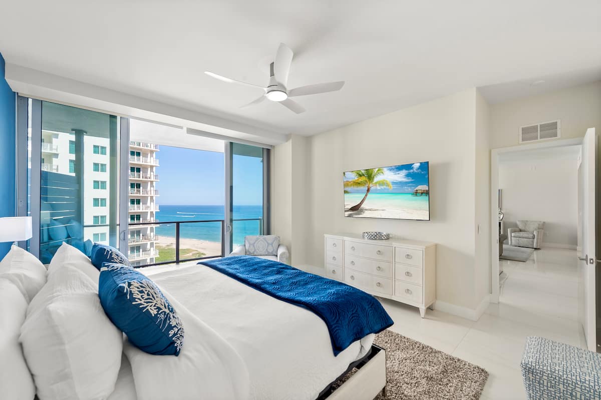 The king suite dressed in sea blues, the ocean visible through the corner window
