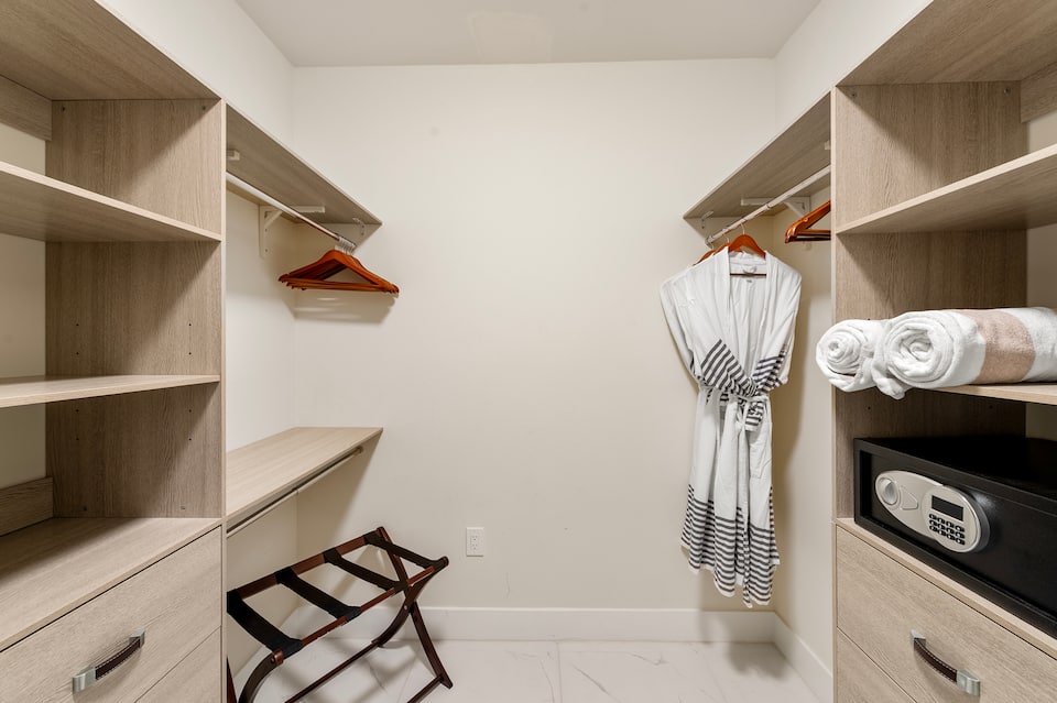The fitted walk-in closet with robes, a luggage rack, shelving and the in-room safe