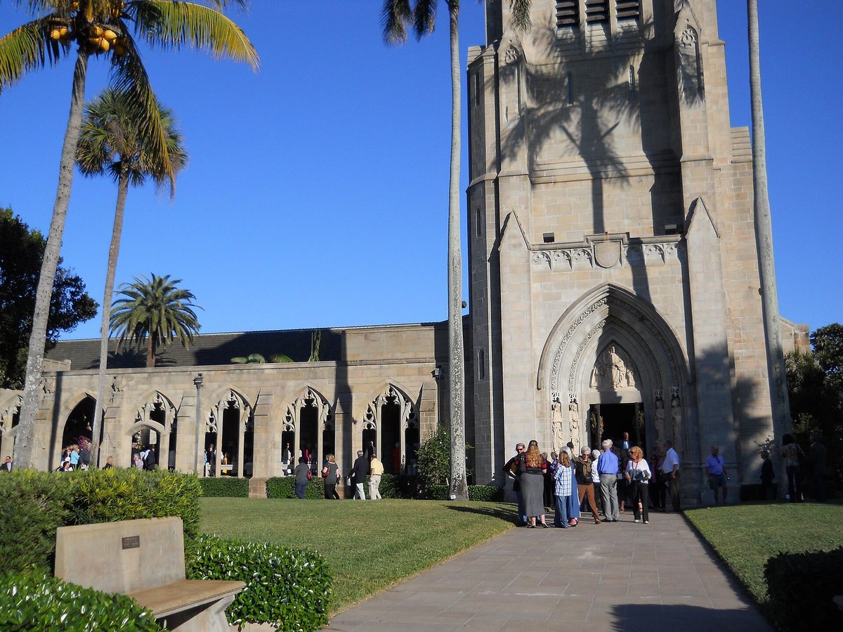 The stone tower and cloister of Bethesda-by-the-Sea church on South County Road, Palm Beach, with palms and visitors