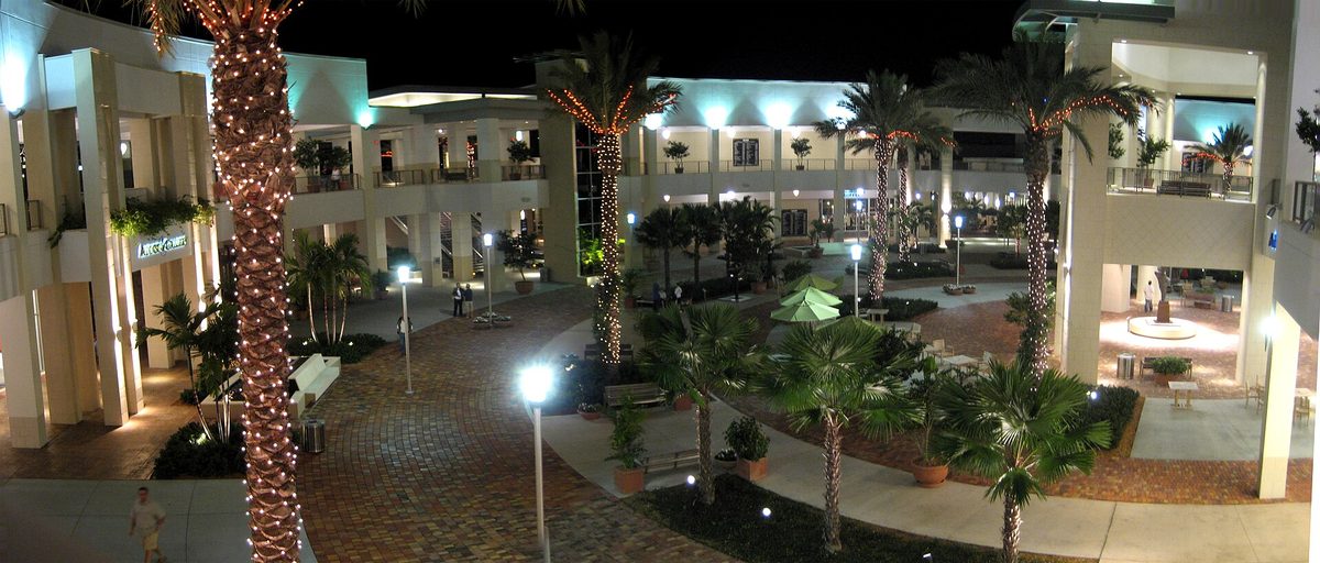The main court at Downtown at the Gardens in Palm Beach Gardens in the evening, with lit palms and shopfronts