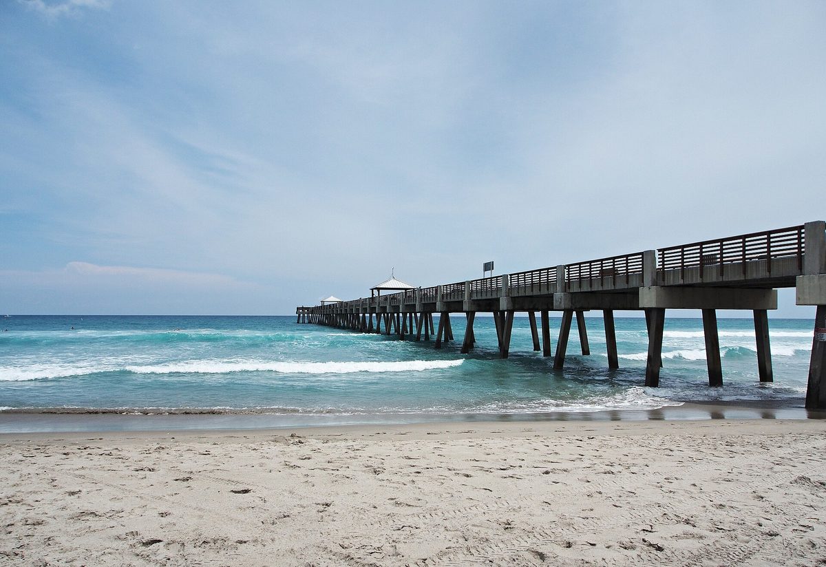 The Juno Beach Pier reaching out over the surf from the sand at Juno Beach