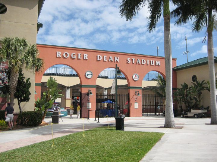 The arched Gate C entrance of the spring training ballpark in Abacoa, Jupiter, under palm trees and a blue sky